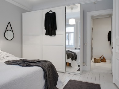 Biała szafa z lutrzanymi drzwiami w skandynawskiej sypialni (21619)