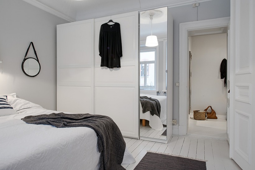 Biała szafa z lutrzanymi drzwiami w skandynawskiej sypialni