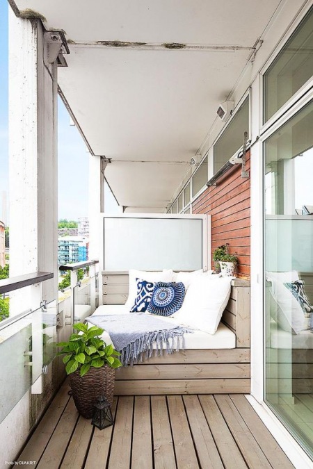 Drewniana podłoga i siedziska z niebieskimi poduszkami na balkonie