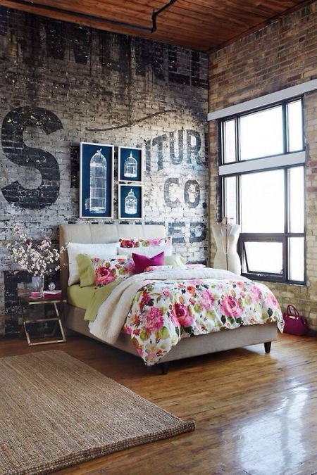 Przestronna sypialnia w lofcie z cegłą na ścianie i ogromną typografią