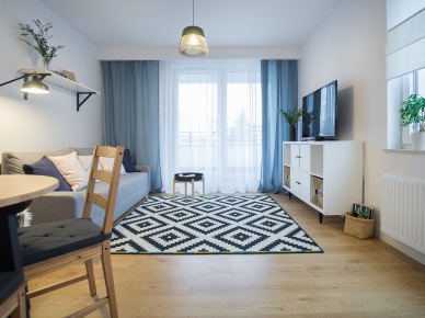Polska aranżacja przytulnego mieszkania z otwartą kuchnią i drewnianą ścianą w sypialni