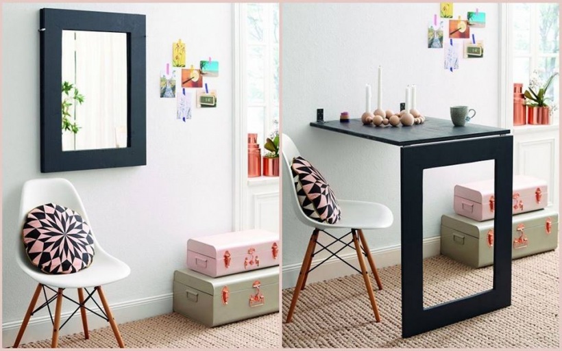 Prostokatne lustro w szerokich czarnych ramach,szara i różowa walizka ozdobna,sznurkowy beżowy dywan,białe nowoczesne krzesło na drewnianych krzyżakach,mała konsolka lada mocowana bokiem do ściany w małym przedpokoju