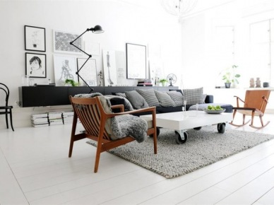 Biały stolik na kólkach,drewniane fotele z lat 60-tych,szara sofa nowoczesna i czarna komoda z lampą na przegubach w salonie z galerią skandynawskich grafik (25680)