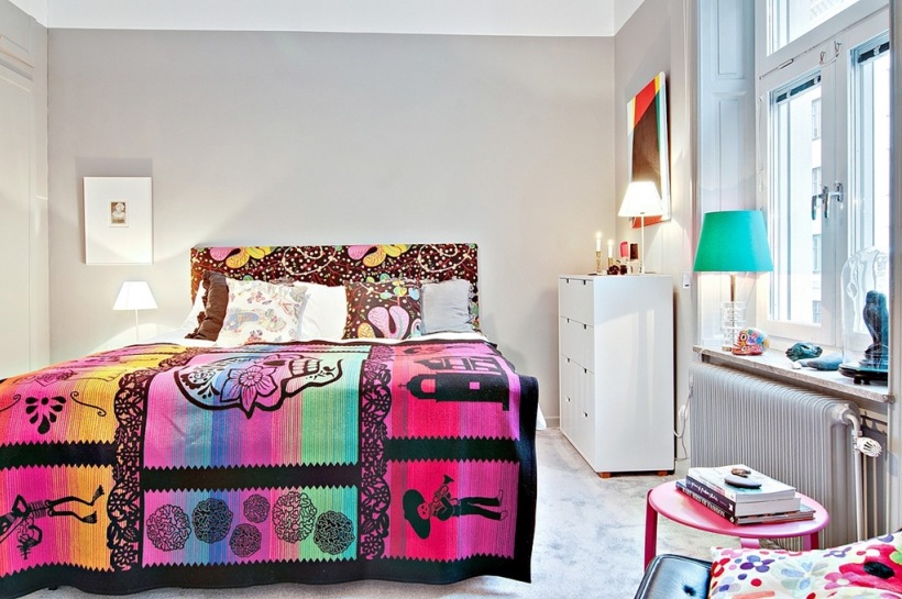 Kolorowe łóżko we wzory w sypialni z szarymi scianami