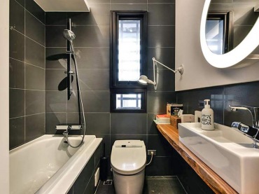 Elegancką aranżację łazienki ociepla drewniany blat pod umywalką. Wnętrze jest całkiem jasne dzięki obecności wąskiego...