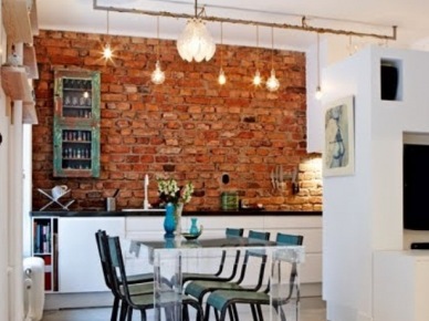 Ekelktyczna kuchnia z nowoczesnym przeźroczystym stołem,industrialnymi turkusowymi krzesłami i szafką w stylu vintage,ścianą z czerwonej cegły i żarówkami na kablu (25272)