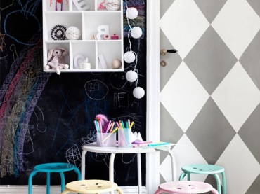 Biało-szara tapeta w romby na drzwiach i czarna ściana z farbą tablicową ,kolorowe metalowe stołki przy okragłym stoliku,półka domek  z bawełnianymi kulami z girlandą (26774)