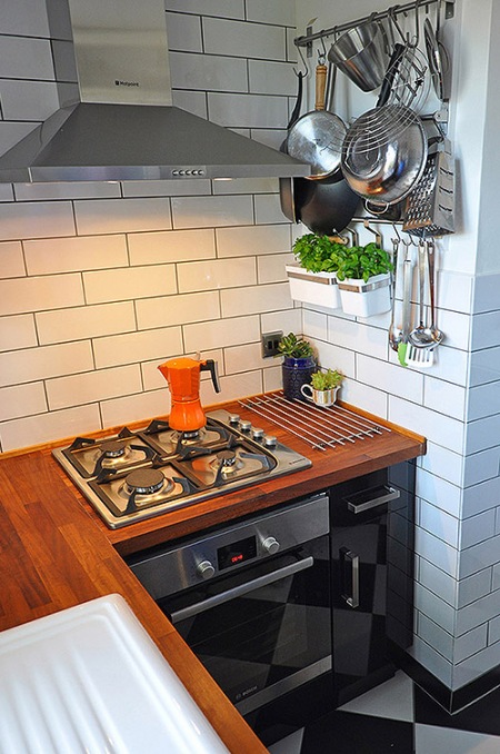 Drewniane blaty i metaliczne półki w białej kuchni