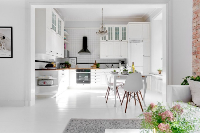 Klasyczna biała kuchnia w stylu skandynawskim otwarta na mały salon