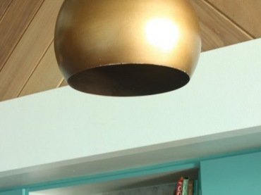 Złote klosze lamp współgrają z innymi złotymi detalami, jakie zastosowano w aranżacji kuchni. Na tle kolorowych szafek...