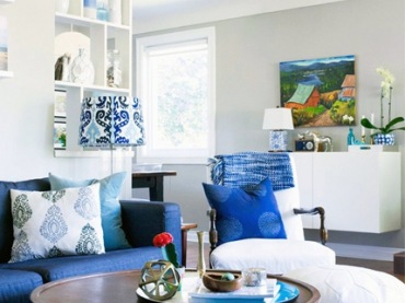 Intensywnie niebieskie obicie sofy w salonie zdecydowanie przyciąga wzrok i tym samym mocno dekoruje przestrzeń. We wnętrzu postawiono na wyraziste dodatki i przytulny klimat, o który dbają drewniane...