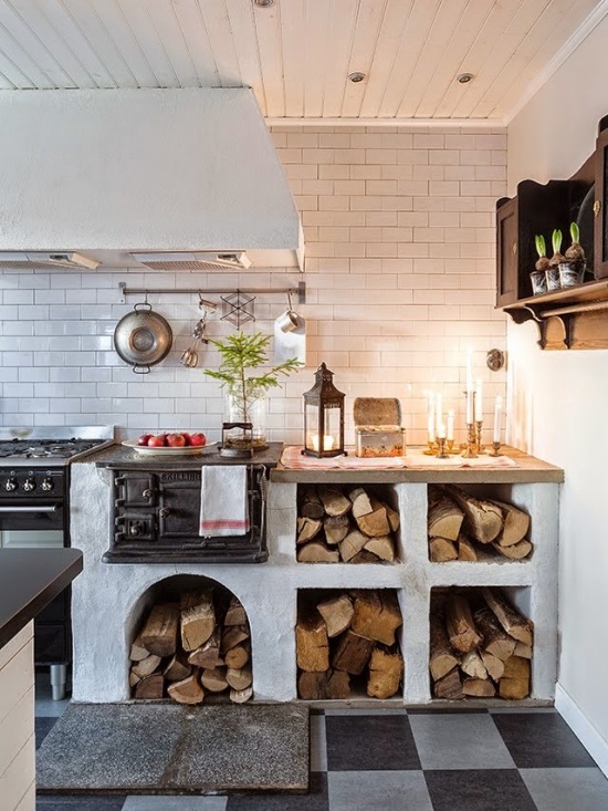 Biała glazurowana cegiełka na ścianie w wiejskiej skandynawskiej kuchni na opałowe drewno, schowki z drewnem pod blatem kuchennym
