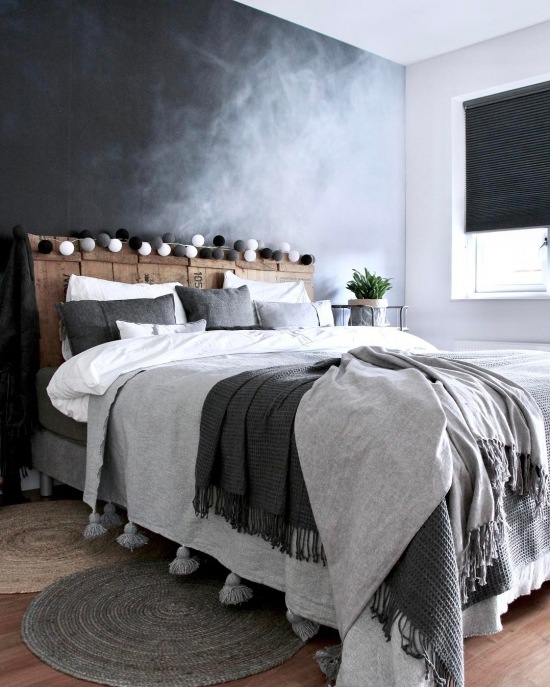 Ciemnoszara ściana i drewniane wezgłowie łóżka w sypialni
