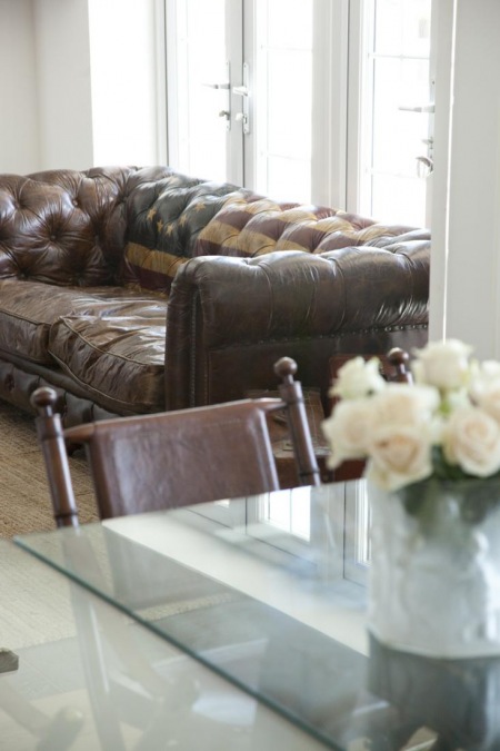 Skórzana, pikowana sofa i kolonialne krzesło w salonie