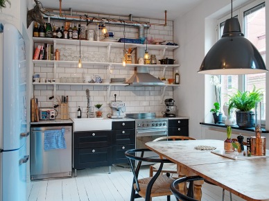 Industrialna kuchnia z odkrytymi półkami na ścianie, białą podłogą z desek,drewnianym stołem i czarną metalową lampą (27128)