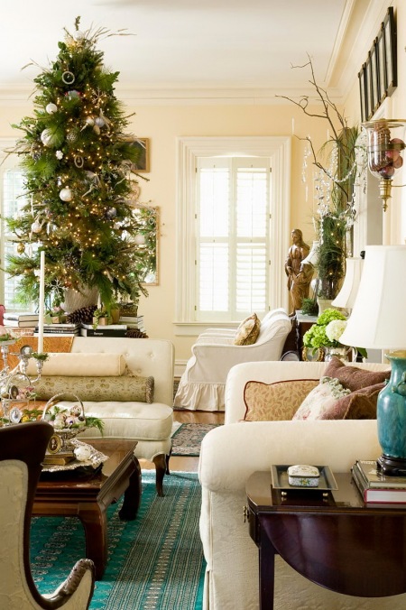 Zielona choinka naturalna w srebrnej dekoracji światecznej w stylowym salonie z białymi fotelami i sofami