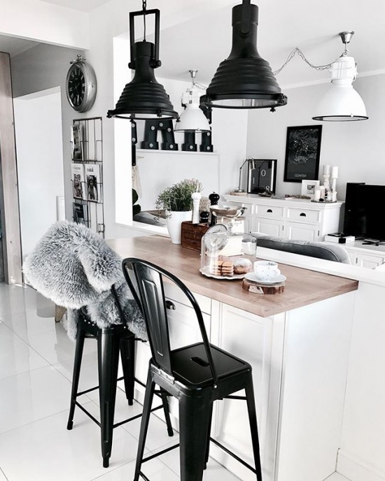 Aranżacja białej kuchni z czarnymi krzesłami i lampami