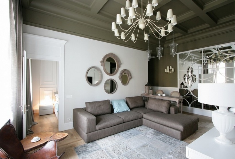 Nowoczesny narożnik,francuskie lustra i żyrandole  i skandynawski dywan w eklektycznym biało-szarym salonie