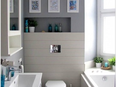 W prostej, biało-szarej łazience znajdują się pojedyncze, ale wpływające na charakter całości dodatki. Obrazki w...