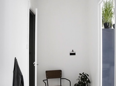 Industrialne metalowe krzesło,białe ściany,czarne drzwi w otwartym przedpokoju w mieszkaniu (26447)