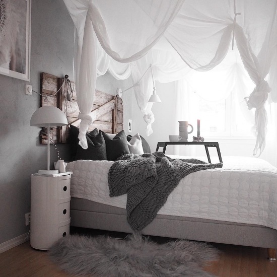 Biały baldachim i drewniane wezgłowie w sypialni