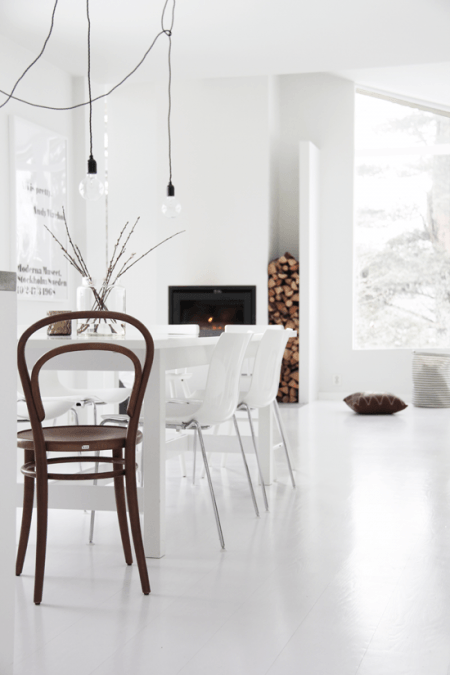 Żarówki na kablu w białym salonie z kominkiem w minimalistycznym stylu