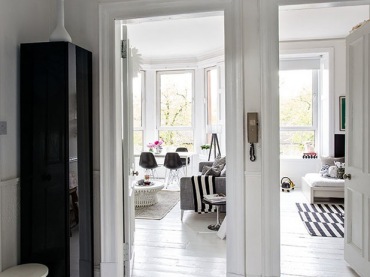 Biały pzredpokój z czarną szafą z widokiem na wnętrze mieszkania w stylu skandynawskim, (21549)