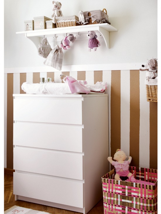 Biała komoda z szufladami i wisząca półka na ścianie z lamperią w biało-brązowe pasy