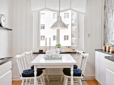Biała roleta rzymska na oknie w kuchni,białe krzesła z drewena z siedziskami i biały prostokatny stół w stylu skandynawskim (28489)