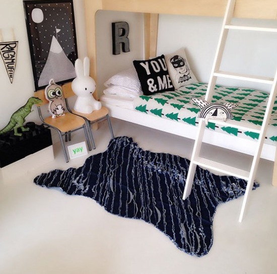 Biała podłoga i ściany, czarne grafiki i biało-czarne poduszki,dywan ze sztucznego futerka i narzuta w zielone choinki