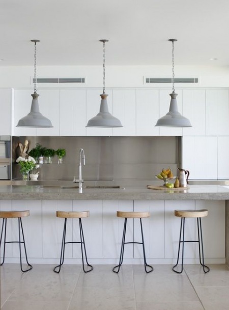 Szare industrialne lampy i metalowe wysokie taborety z drewnianymi siedziskami w nowoczesnej kuchni