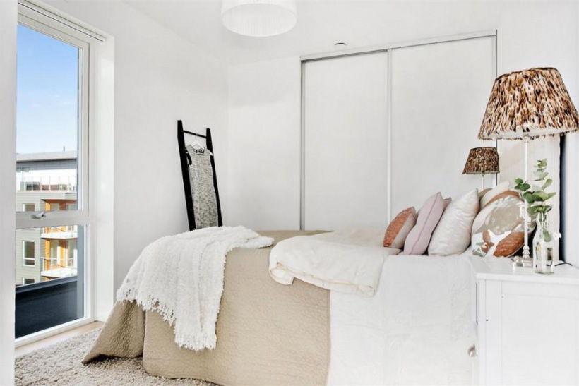Biała minimalistyczna sypialnia w skandynawskim   stylu z pastelowymi dodatkami w kolorach ziemi