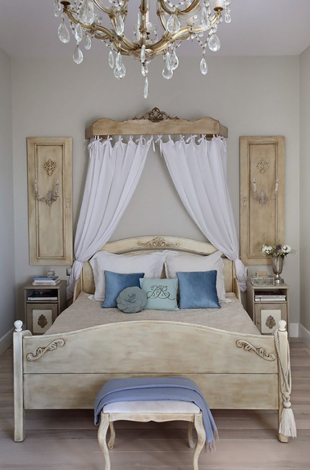 Ozdony baldachim w stylu prowansalskim,drewniane stylowe łóżko z bielonego drewna,niebieskie poduszki i ozdobne panele francuskie z drewna