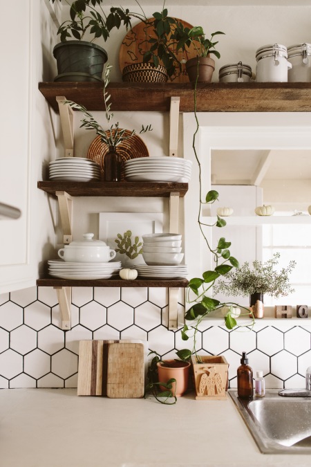 Białe naczynia i kwiaty na drewnianych półkach w kuchni