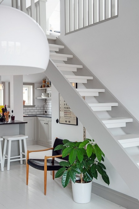 Ażurowe białe schody w otwartej przestrzeni dwupoziomowego mieszkania