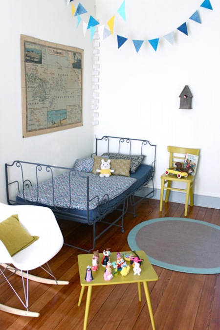 Niebieskie łóżko metalowe i proporczyki w pokoju