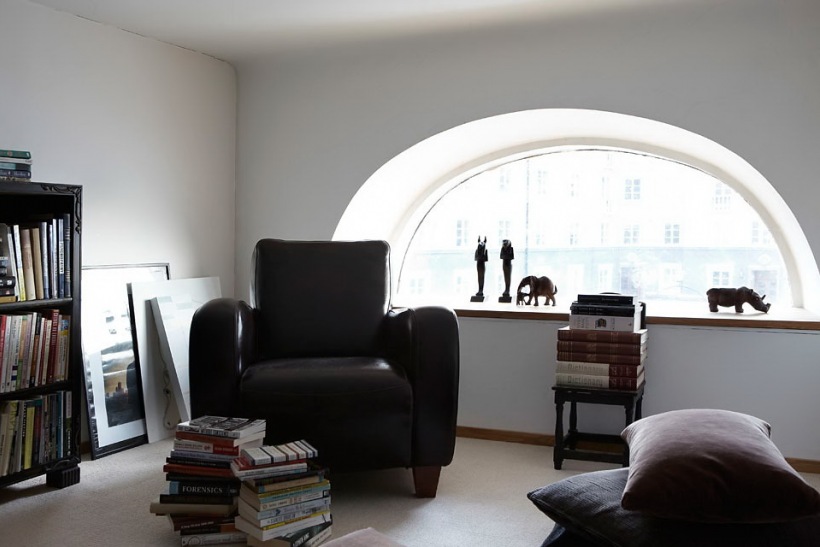 Pokój wypoczynkowy ze skórzanym fotelem na antresoli  w wysokim mieszkaniu