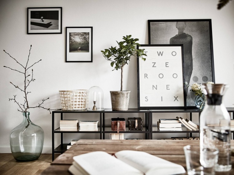 Czarna metalowa szafka z otwartymi półkami,szklany słój na podłodze,nowoczesne biało-czarne fotografie i grafiki w dekoracji skandynawskiego salonu