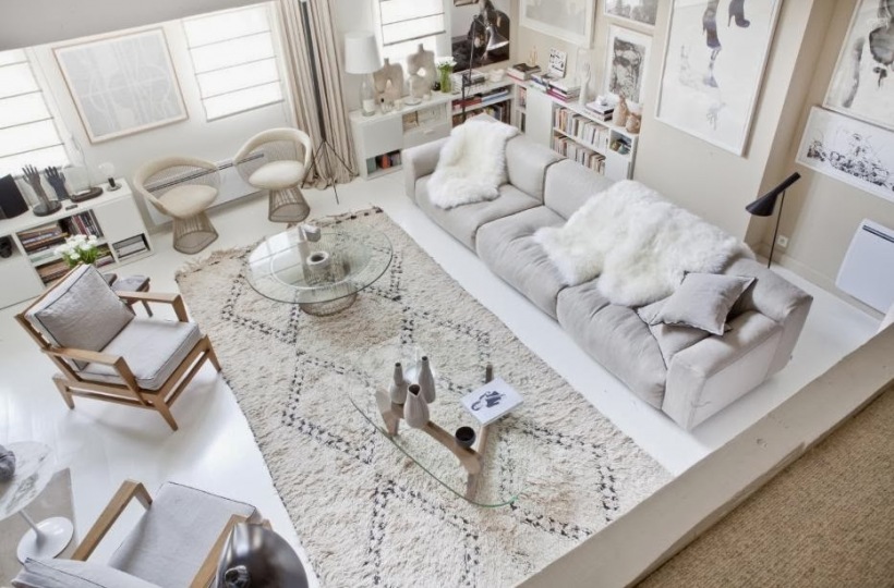 Szara nowoczesna sofa,marokański biały dywan,dizjnerskie krzesła i szklane stoliki kawowe w biało-beżowym salonie