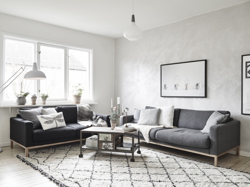 Szare i czarne sofy w stylu skandynawskim , industrialny stolik na kółkach,dywan berberys na podłodze w salonie