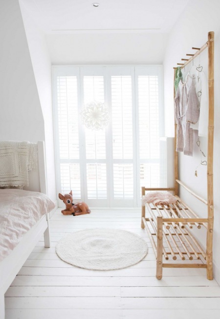 Biała sypialnia dla dziecka z drewnianą ażurową ławką z wieszakami