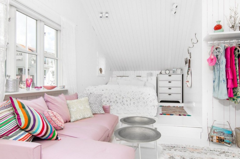 Różowy narożniik,kolorowe poduszki w paski,srebrne stoliki z tacą okragłą w białej sypialni