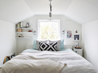 Jasna i wąska sypialnia ze skosami też może być ciekawie urządzona.Otwarte półeczki po oby stronach łóżka to świetny pomysł przy wąskim pokoju.I oczywiście biel, która optycznie powiększa...