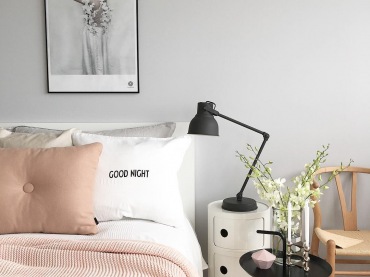 Szarość na ścianie w sypialni stanowi neutralne tło dla dodatków w innych odcieniach. Koc i poduszka w pastelowym różu wnoszą do wnętrza romantyczny...