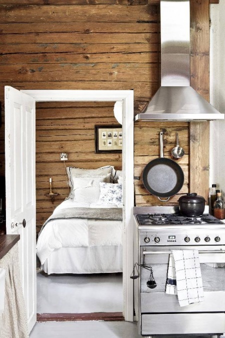 Ściany z drewnianych bali,biała stolarka i stalowy okap w kuchni