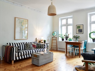 Drewniany stół z niebieskimi i białymi krzesłami,sofa w biało-czarne pasy,drewniana szara skrzynia w salonowym mixie (26650)