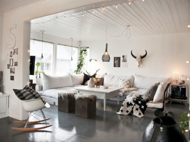 Biały otwarty salon z grafitową podłogą,girlandą z żarówkami, białymi sofami i fotelem na płozach (47885)