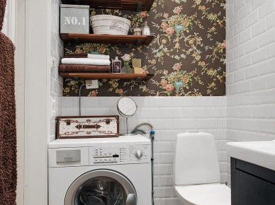 Biała glazurowana cegiełka na ścianie w łazience,brązowa tapeta w kolorowe stylowe kwiaty,drewniane pólki i drewnopodobna ceramiczna płytka na podłodze (25857)