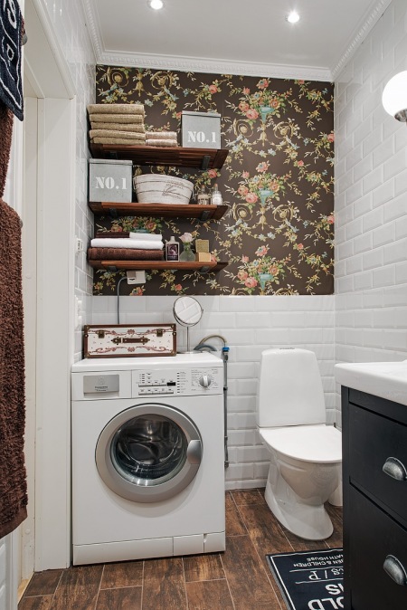 Biała glazurowana cegiełka na ścianie w łazience,brązowa tapeta w kolorowe stylowe kwiaty,drewniane pólki i drewnopodobna ceramiczna płytka na podłodze