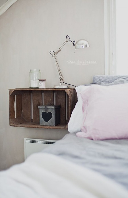 Drewniana skrzynka i srebrna lampka w sypialni
